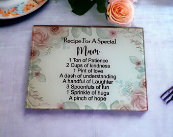 May include: A glass plaque with a floral design and the text "Recipe For A Special Mum 1 Ton of Patience 2 Cups of kindness 1 Pint of love A dash of understanding A handful of Laughter 3 Spoonfuls of fun 1 Sprinkle of hugs A pinch of hope"