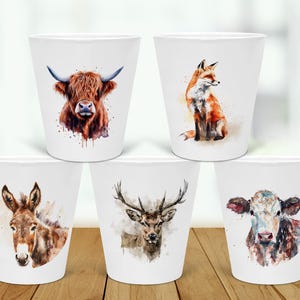 May include: Set of five white ceramic mugs with watercolour animal illustrations. The mugs feature a highland cow, a fox, a donkey, a deer, and a cow.