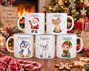 May include: Five white ceramic mugs featuring festive holiday characters including Santa Claus, a reindeer, a penguin, a polar bear, and an elf. Each mug is personalized with names including Charlie, Isabelle, Mummy, Nanny, and Daddy, decorated with candy canes and snowflakes.