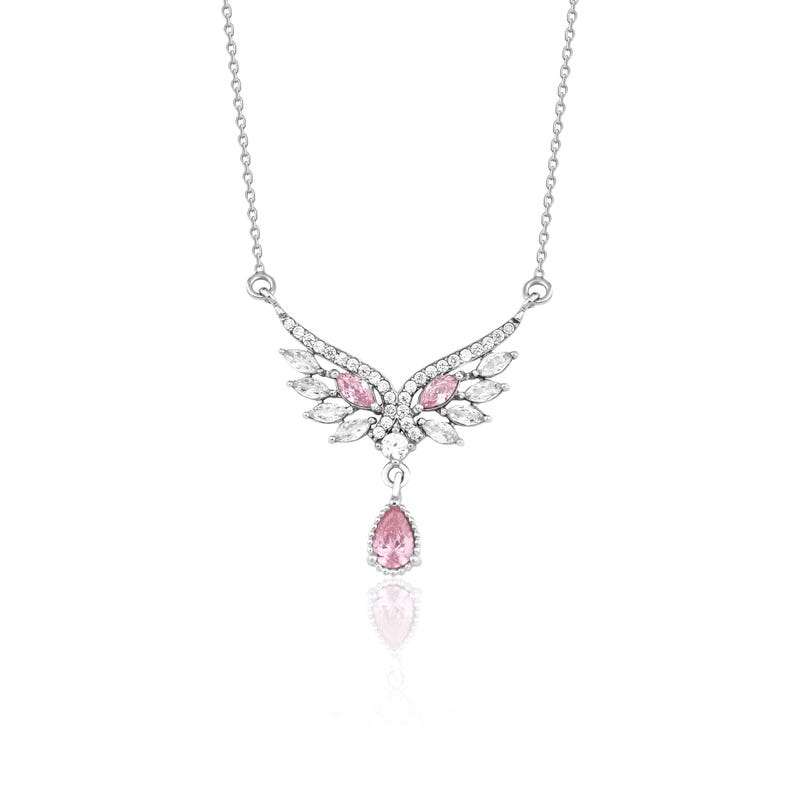 Peut inclure: Collier argent&eacute; avec un pendentif en forme d'ailes orn&eacute; de pierres roses et blanches. Une pierre rose en forme de goutte pend en dessous. Le collier est pr&eacute;sent&eacute; sur fond blanc.