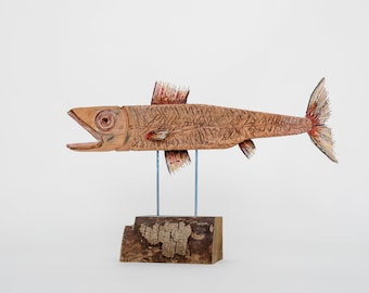 May include: A wooden fish sculpture with painted details, mounted on a wooden base. The fish has a brown body with red and yellow accents. The sculpture is a unique and decorative piece.