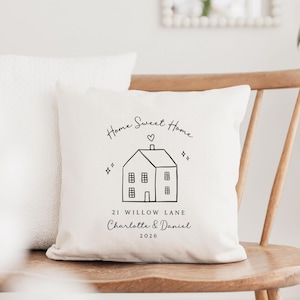May include: Cream-colored throw pillow with a black line drawing of a house, heart, and the words "Home Sweet Home." Below the house is the text "21 Willow Lane Charlotte & Daniel 2026." Another white pillow is behind it.