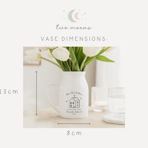 May include: White ceramic vase with a handle, holding white tulips. The vase has a house graphic and the text "Home Sweet Home". The vase is 13 cm tall and 8 cm wide.