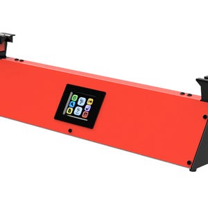 May include: A red electronic device with a black screen displaying icons. The device has a rectangular shape with black supports on each end. The device is designed to sit on a flat surface.