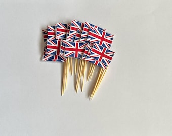 May include: A stack of small Union Jack flags on wooden skewers. The flags are red, white, and blue.