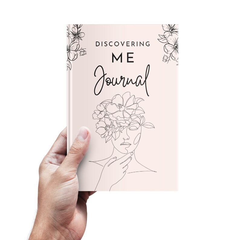 K&ouml;nnte beinhalten: Ein rosa Notizbuch mit dem Text "DISCOVERING ME Journal" und einer Strichzeichnung einer Frau mit Blumen auf dem Kopf.