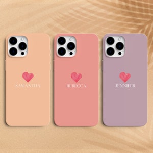 Può includere: Tre custodie per telefono di colori e nomi diversi. La prima custodia è pesca con il nome Samantha, la seconda custodia è rosa con il nome Rebecca e la terza custodia è viola con il nome Jennifer. Ogni custodia ha un cuore rosa con un design ad acquerello.