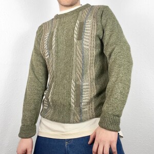 May include: A green knitted sweater with a geometric pattern in beige, brown, and blue.