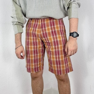 Op de afbeelding: Rode en oranje geruite shorts met een witte achtergrond. De shorts hebben een ontspannen pasvorm en zijn gemaakt van een lichtgewicht stof.