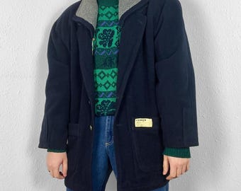 Puede incluir: Una chaqueta de forro polar azul marino con cuello de forro polar gris y un parche en el bolsillo izquierdo que dice "CLOSED". La chaqueta tiene cierre de botones y dos bolsillos.