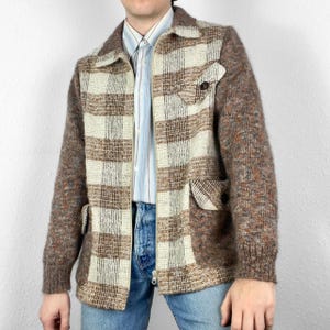 May include: A brown and white plaid jacket with a zipper closure. The jacket has a brown knit sleeve and a brown knit pocket on the front.