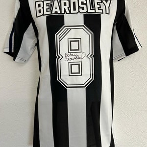 Op de afbeelding: Zwart-wit gestreept voetbal shirt met de naam "BEARDSLEY" en het nummer "8" op de rug. Het shirt is gesigneerd door "Peter Beardsley".
