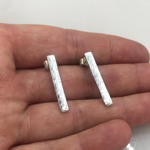 May include: A pair of silver hammered bar earrings. The earrings are simple and modern, and they would be a great addition to any jewellery collection.