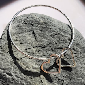 Sterling silver hammered bangle with two silver hearts