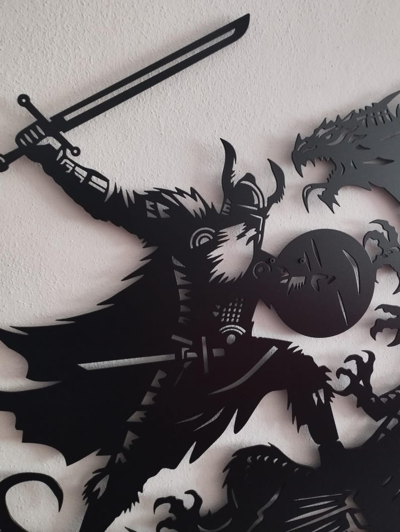 May include: Black metal wall art depicting a warrior with a sword fighting a dragon. The warrior is wearing armor and a helmet with horns. The dragon is attacking the warrior with its claws and teeth.