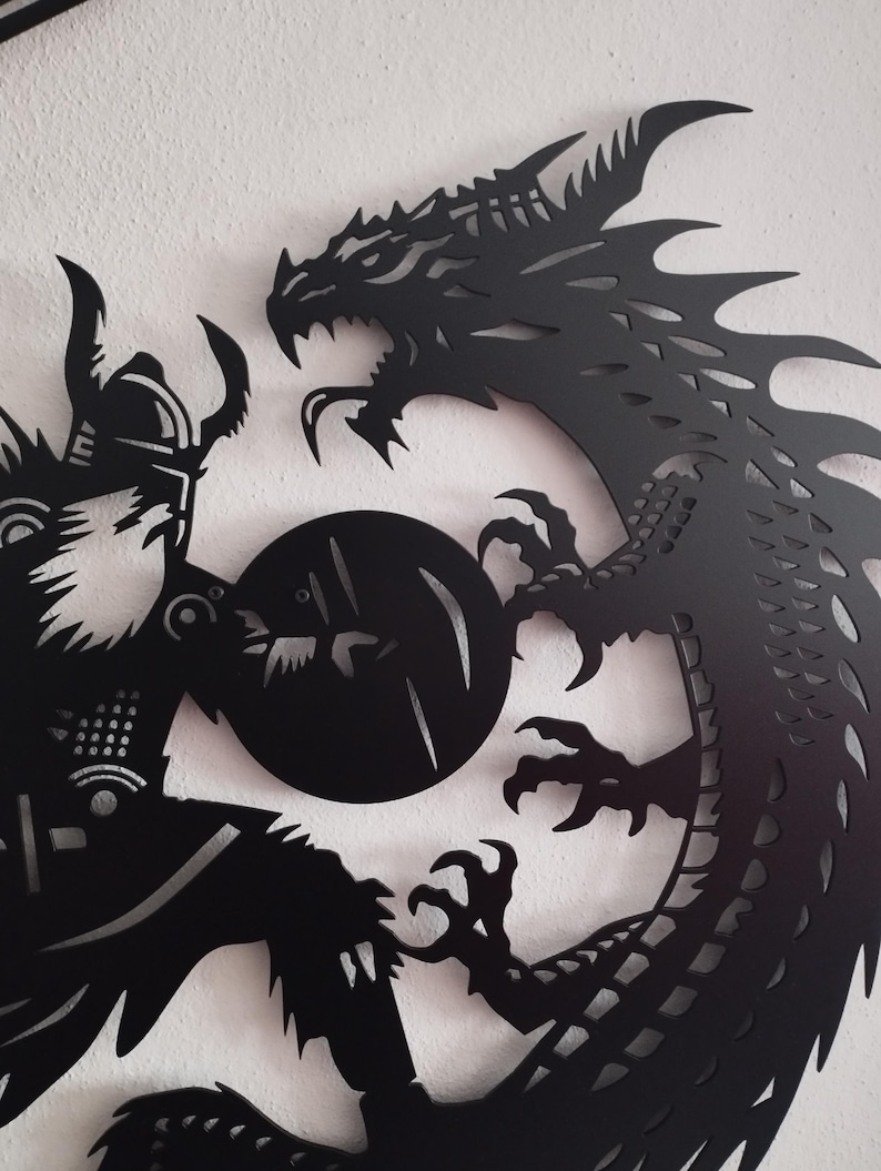 May include: Black metal wall art featuring a silhouette of a dragon and a warrior in combat. The dragon is curled around the warrior, its claws extended. The warrior is holding a shield and a sword.
