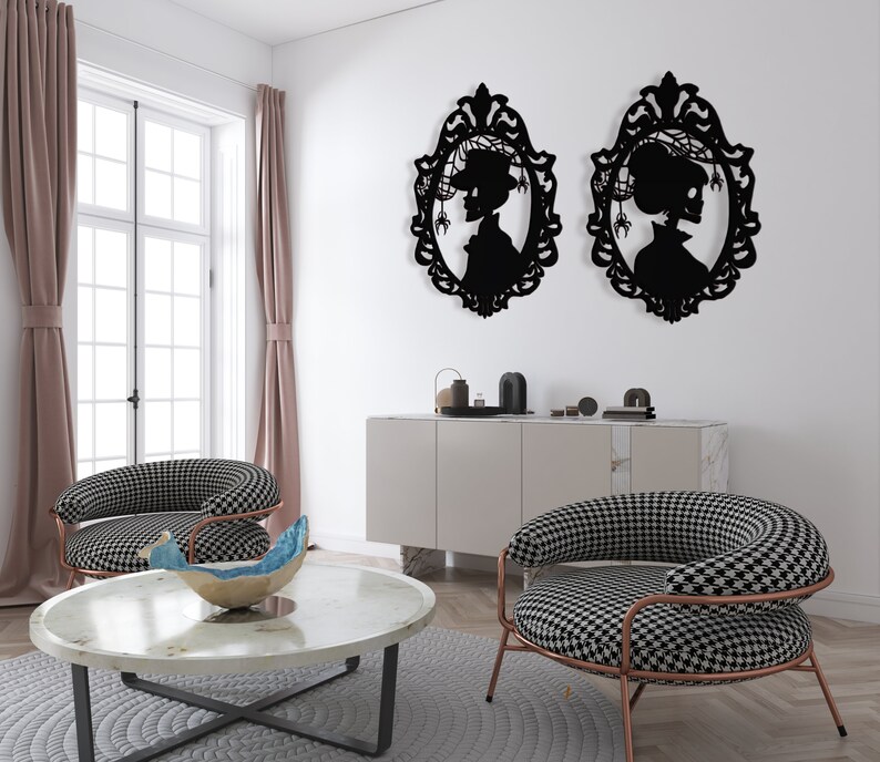 Pode incluir: Duas pe&ccedil;as de decora&ccedil;&atilde;o de parede em silhueta preta em forma de molduras ovais com um perfil de mulher dentro de cada moldura. As molduras s&atilde;o decoradas com desenhos intrincados. A decora&ccedil;&atilde;o de parede est&aacute; pendurada em uma parede branca acima de um arm&aacute;rio branco com duas cadeiras de padr&otilde;es preto e branco na frente.