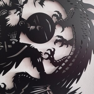 May include: Black metal wall art depicting a Viking warrior with a shield facing a dragon. The warrior is holding a sword and the dragon is in a defensive posture.