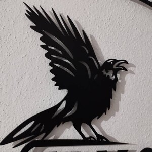 May include: Black metal silhouette of a raven with wings spread, perched on a sign that reads "Nevermore".