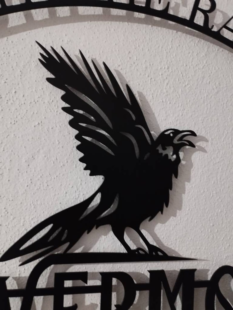 May include: Black metal silhouette of a raven with wings spread, perched on a sign that reads "Nevermore".
