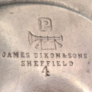 May include: Close-up of a silver mark with the letter "P" above a stylized trumpet with a banner and the text "JAMES DIXON & SONS SHEFFIELD 4".