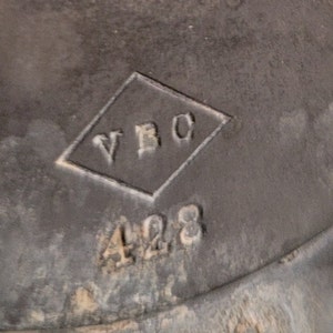May include: Close-up of a black metal object with a diamond-shaped mark that says "VBC" and the number "428" below it.