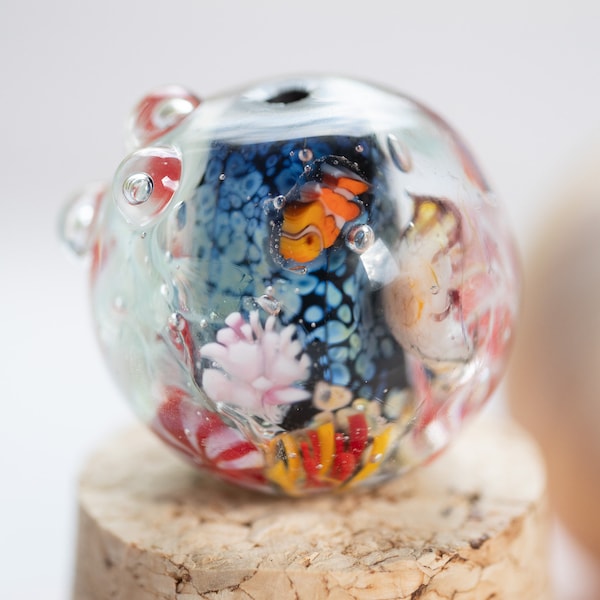 Perle d'aquarium de récif de corail avec méduses, poisson-clown dans des anémones, algues, bulles et étoiles de mer.