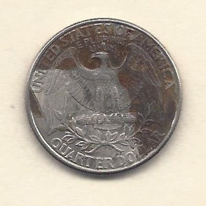 Può includere: Una moneta d'argento da un quarto di dollaro con un'aquila e le scritte "United States of America" e "Quarter Dollar". La moneta presenta un design dettagliato e un aspetto leggermente usurato.
