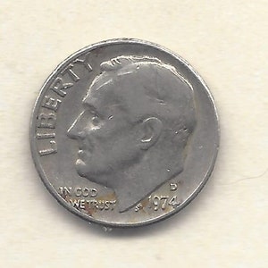 May include: A silver United States dime coin, with a profile of a man and the word "LIBERTY". The coin also shows the text "IN GOD WE TRUST" and the year "1974".