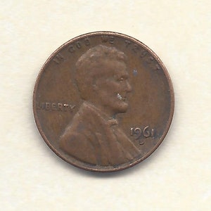 Può includere: Una moneta da un centesimo Lincoln del 1961, color rame. Il dritto presenta un profilo di Abraham Lincoln, con le parole "LIBERTY" e "IN GOD WE TRUST". L'anno "1961" è anch'esso visibile.