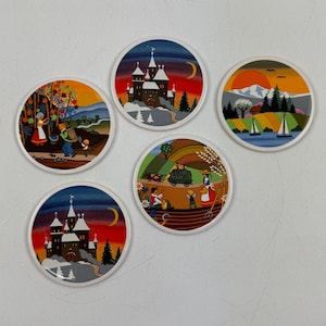 May include: A set of five circular coasters with vibrant folk art illustrations. Each coaster displays a unique scene, such as castles, landscapes, and figures. The coasters have a white edge and are probably made of ceramic or a similar material.