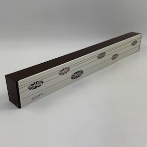 以下が含まれることがあります： 長方形の銀色のキッチン用品ホルダーで、濃い茶色のトップが付いています。 ホルダーには繰り返しの花の模様と、赤色の「brabantia」のブランド名があります。 キッチン用品を収納するように設計されています。