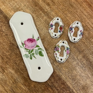 May include: A set of three ceramic mugs with a speckled, matte finish. The mugs are in shades of cream, light gray, and dark gray. Each mug has a simple, minimalist design and a rounded handle.