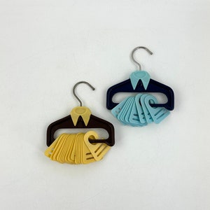 Op de afbeelding: Twee sets plastic hangers, de ene set is bruin met gele hangers en de andere is blauw met lichtblauwe hangers.