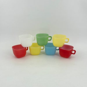 Könnte beinhalten: Satz von sechs bunten Glasbechern mit Henkeln. Die Becher sind in den Farben Rot, Gelb, Grün, Blau und Weiß.