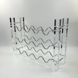 Peut inclure: Un porte-bouteilles en acrylique transparent avec un design en fil métallique argenté. Le porte-bouteilles comporte plusieurs niveaux pour ranger les bouteilles de vin.