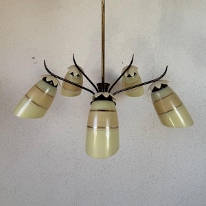 Op de afbeelding: Een vijf-lichts hanglamp met een messing afwerking en crèmekleurige glazen lampenkappen. De lampenkappen hebben een subtiel gouden streepmotief.