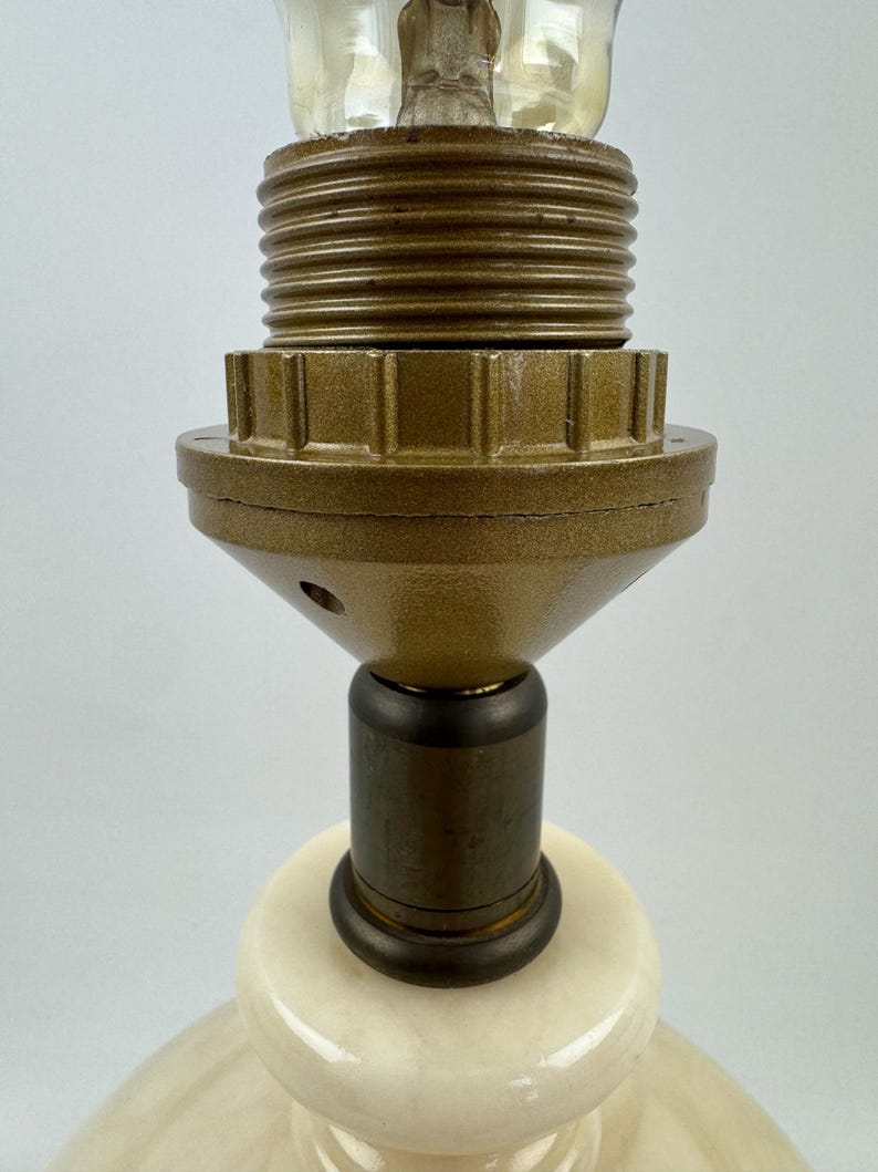 Peut inclure: Gros plan sur un pied de lampe cr&egrave;me avec un col en m&eacute;tal couleur laiton et une douille. Le pied de la lampe est de forme arrondie et la douille est con&ccedil;ue pour accueillir une ampoule standard. La lampe est probablement pour la d&eacute;coration int&eacute;rieure.