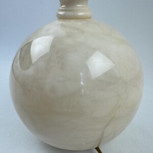Peut inclure: Un pied de lampe sph&eacute;rique cr&egrave;me avec un motif marbr&eacute;. La base a une forme bulbeuse et un col d&eacute;coratif menant &agrave; un dessus marron fonc&eacute;. Un cordon dor&eacute; s'&eacute;tend de la base.