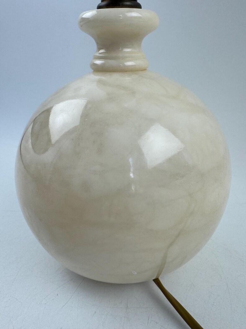 Peut inclure: Un pied de lampe sph&eacute;rique cr&egrave;me avec un motif marbr&eacute;. La base a une forme bulbeuse et un col d&eacute;coratif menant &agrave; un dessus marron fonc&eacute;. Un cordon dor&eacute; s'&eacute;tend de la base.