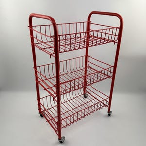 May include: A red metal utility cart with three wire baskets and a handle. The cart has four small wheels for easy movement. The overall design is simple and functional, suitable for storage.