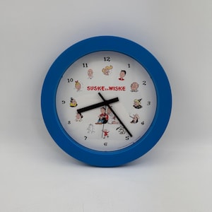 Puede incluir: Un reloj de pared redondo azul con una esfera blanca que presenta personajes de la tira cómica "Suske en Wiske". El reloj tiene manecillas negras y números negros.