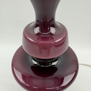 May include: A burgundy glass table lamp with a layered design and a brass base.