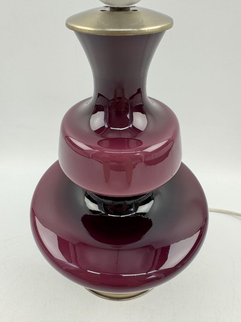 May include: A burgundy glass table lamp with a layered design and a brass base.