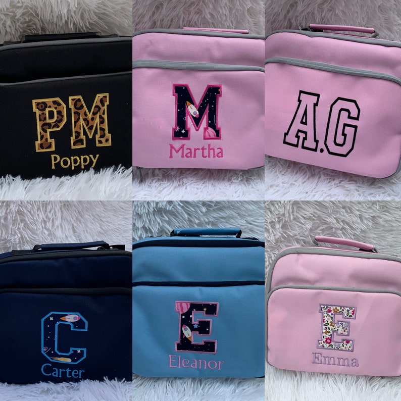 May include: Six personalized lunch bags with different colors and designs. The bags are black, pink, blue, and light blue. Each bag has a large letter embroidered on the front with a name underneath. The letters are "P", "M", "A", "C", "E", and "E". The names are "Poppy", "Martha", "AG", "Carter", "Eleanor", and "Emma".