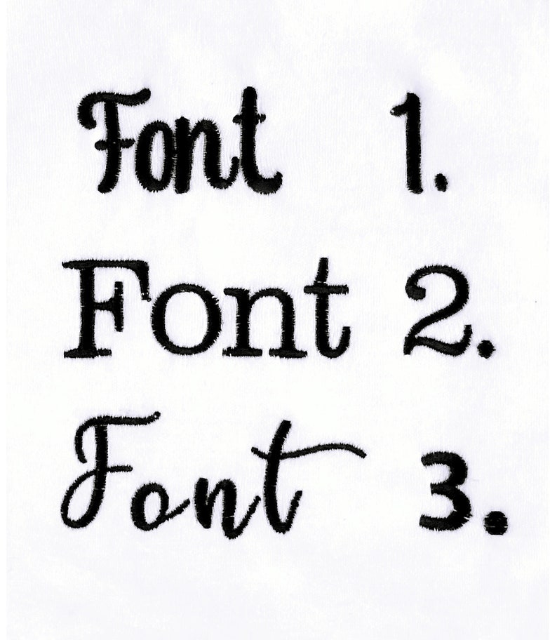 May include: Three distinct black embroidered text samples on a white fabric background. The first line reads Font 1, the second line reads Font 2, and the third line reads Font 3. Each line displays a different typeface style in black thread.