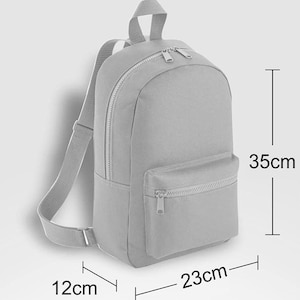 May include: A light gray backpack with a main zippered compartment, a smaller front zippered pocket, and adjustable shoulder straps. The backpack measures 35 cm in height, 23 cm in width, and 12 cm in depth as indicated by the visible dimension lines.