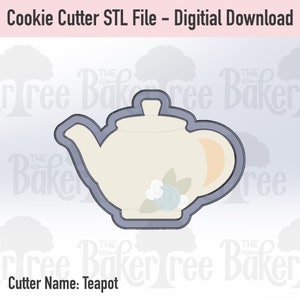 May include: A grey cookie cutter in the shape of a teapot with a white body and a light blue flower design. The cutter is for making cookies.