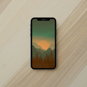 Puede incluir: Un smartphone negro muestra un fondo de pantalla con temática de naturaleza. El fondo de pantalla presenta una puesta de sol sobre una cordillera con pinos en primer plano. El cielo hace la transición de verde a naranja.