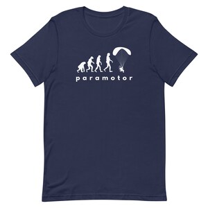 May include: A navy blue t-shirt featuring a white graphic of the evolution of man, culminating in a person flying a paramotor. The text "paramotor" is printed beneath the graphic.